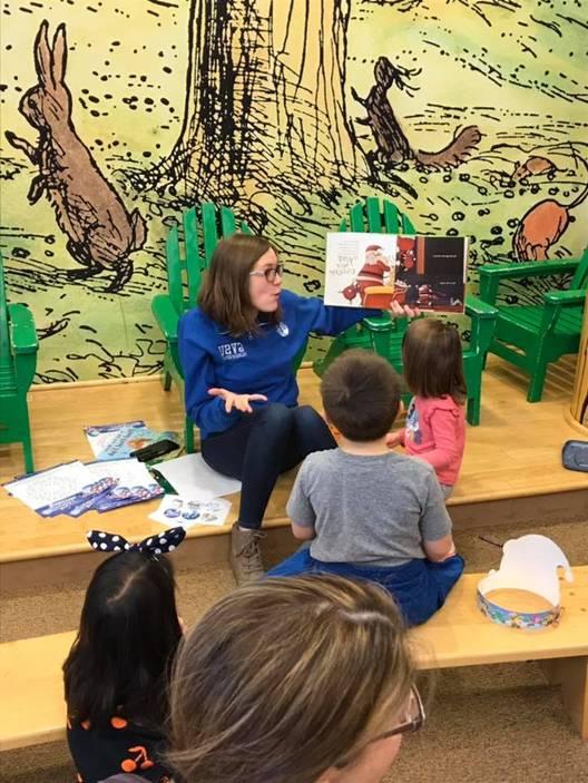 Ellie reading a picture book to young students